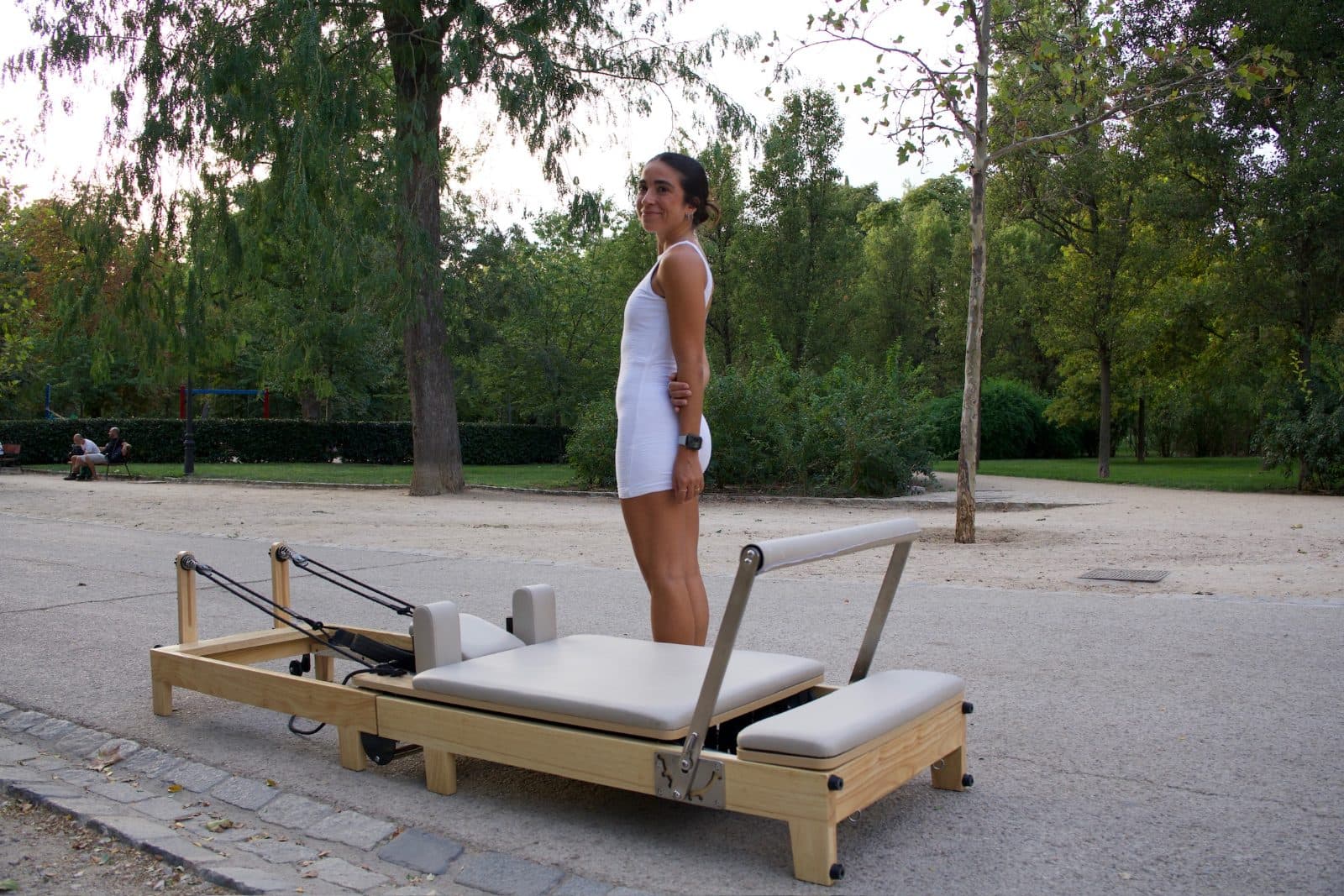 Reformer de Pilates plegable de madera junto a la instructora