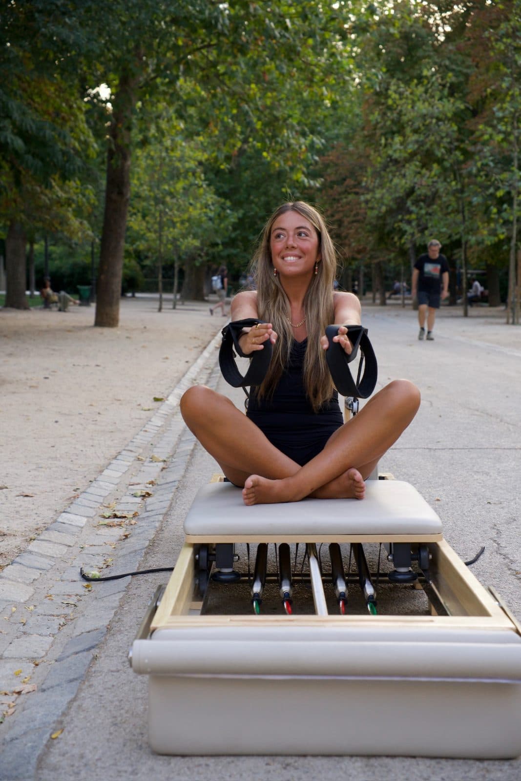 Alumna sonriendo, sentada en el reformer con las correas